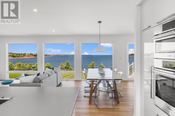 Dining area with a glass table and chairs in front of large windows with water and landscape views. - 73 Four Winds Lane, Stanley Bridge, Stanley Bridge