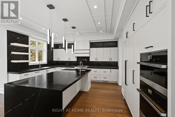 Modern kitchen with black marble island, white cabinets, and pendant lights - 73 Harding Boulevard Richmond Hill