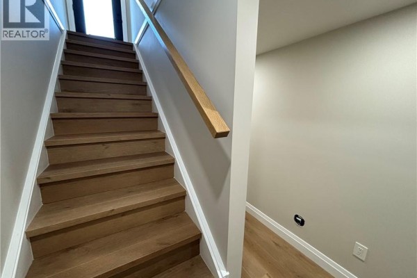 Wooden staircase with light oak treads and white risers, leading upwards with a minimalist handrail. - 73 Mary Street Unit# 1b, Brantford