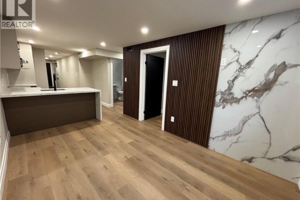 Interior view showing a modern kitchen island, a black door, and a decorative wall with dark wood slats and marble pattern. - 73 Mary Street Unit# 1b, Brantford
