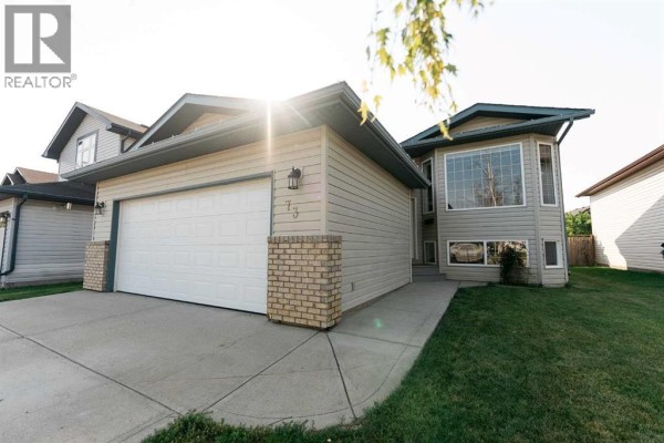 Front door of a beige house with grey steps, concrete path, and large windows. - 73 Ogilvie Close, Red Deer