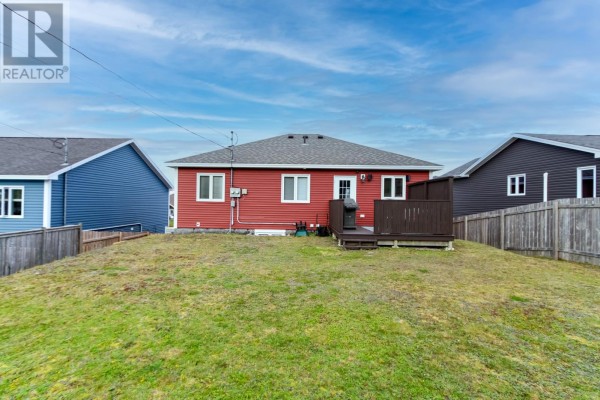 Rear view of a red house with a wooden deck and fenced backyard. - 73 Sgt. Donald Lucas Drive, Paradise