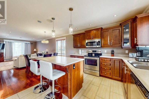 Open concept kitchen and living room with dark wood cabinets and island seating. - 73 Sgt. Donald Lucas Drive, Paradise