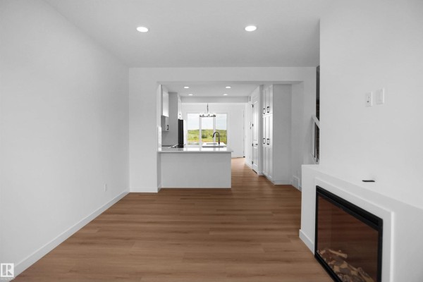 Open concept living space showing the living room, kitchen island, and cabinets, with light wood floors. - 73 Sienna Bv, Fort Saskatchewan