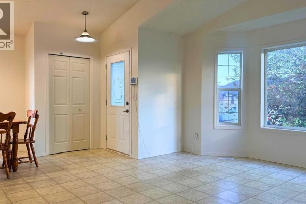 View of the entryway with double closet doors and a front door, adjacent to a living area. - 7302 104a Street, Grande Prairie