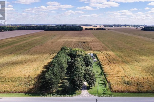 Aerial view of a farmhouse surrounded by agricultural fields of corn under a partly cloudy sky. - 73080 Airport Line, Bluewater