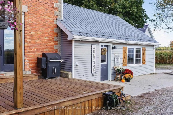 Wooden deck and outdoor grill next to a light grey siding structure with wooden shutters. - 73080 Airport Line, Bluewater