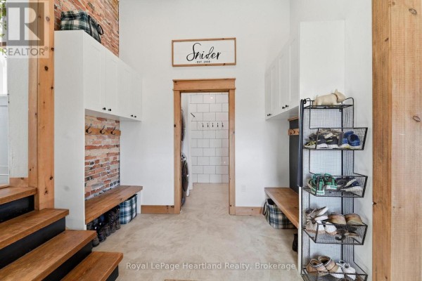 Mudroom with white cabinets, wooden benches, exposed brick, and a doorway to a laundry room. - 73080 Airport Line, Bluewater