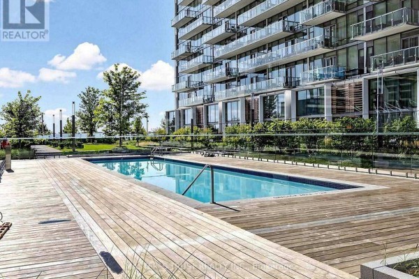 Outdoor swimming pool with a wooden deck and glass railing. - 731 - 39 Queens Quay E, Toronto