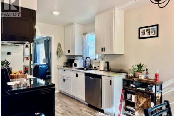 White kitchen cabinets, stainless steel dishwasher, and countertop with sink and appliances. - 731 13th Street, Humboldt