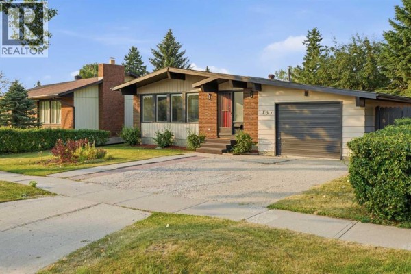 A wide angle exterior shot of the house showing the driveway and front yard landscaping. - 731 Queensland Drive Se, Calgary