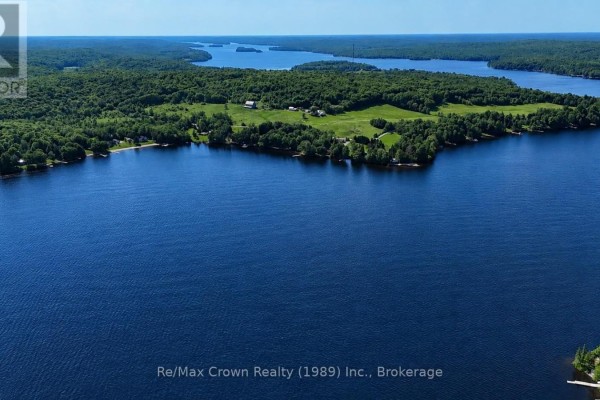 Distant aerial view of the blue house and surrounding waterfront property. - 7313 534 Highway, Parry Sound Remote Area