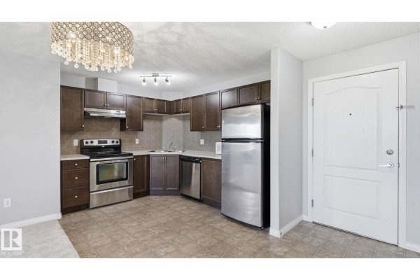 Corner kitchen with dark wood cabinets, stainless steel appliances, and tiled floor. - #7319 7327 South Terwillegar Dr Nw, Edmonton