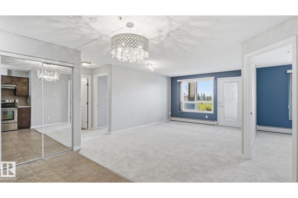 Spacious living area with a large crystal chandelier and a view of the outdoors. - #7319 7327 South Terwillegar Dr Nw, Edmonton