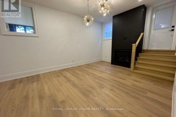 A living area with light wood floors, white walls, and a black fireplace surround. - 732 West Shore Boulevard, Pickering