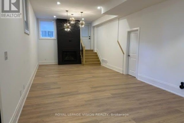 A spacious living area with light wood floors, white walls, and a black fireplace surround. - 732 West Shore Boulevard, Pickering
