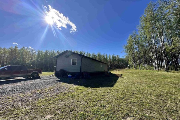Side view of a grey residential structure with white trim and a red pickup truck parked nearby. - 7323 Twp Road 512, Rural Parkland County