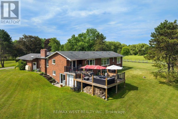 Wide view of a spacious garage with an open bay door, concrete floor, storage cabinets, and a car lift. - 7324 Highway 9 Road S, New Tecumseth