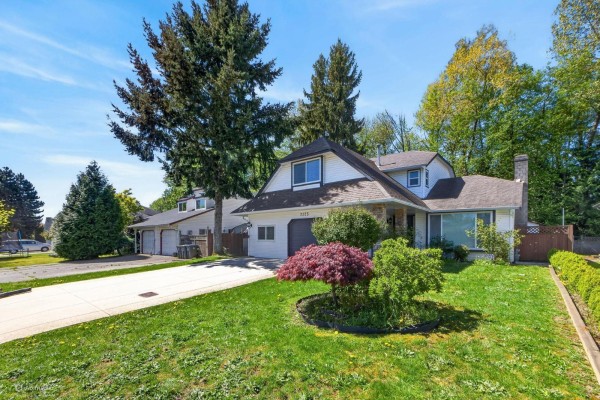 Front view of a two-story white house with a sloped roof, manicured lawn, and red Japanese maple tree. - 7325 123 Street, Surrey