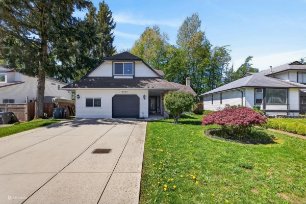Facade of a white residential house with a dark garage door, white siding, and landscaped front yard. - 7325 123 Street, Surrey