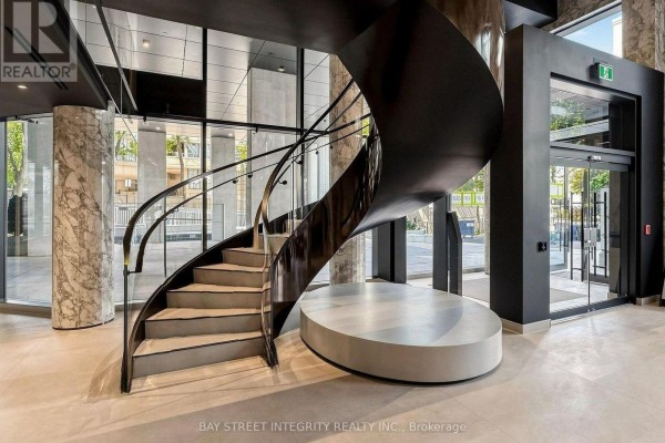 Modern lobby featuring a black spiral staircase with glass railings and marble columns. - 733 - 91 Montclair Avenue, Toronto
