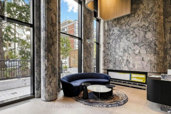 Lobby seating area with a curved blue sofa, marble walls, and large windows. - 733 - 91 Montclair Avenue, Toronto