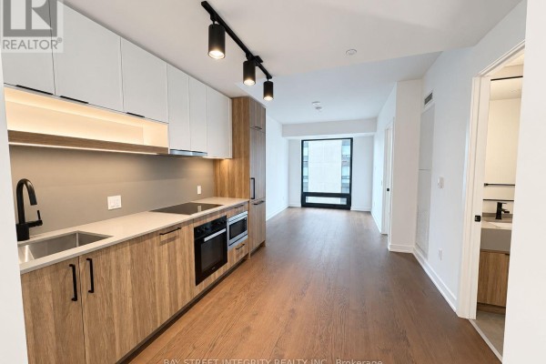 Apartment kitchen with light wood cabinetry, grey countertops, stainless steel appliances, and dark wood floors. - 733 - 91 Montclair Avenue, Toronto