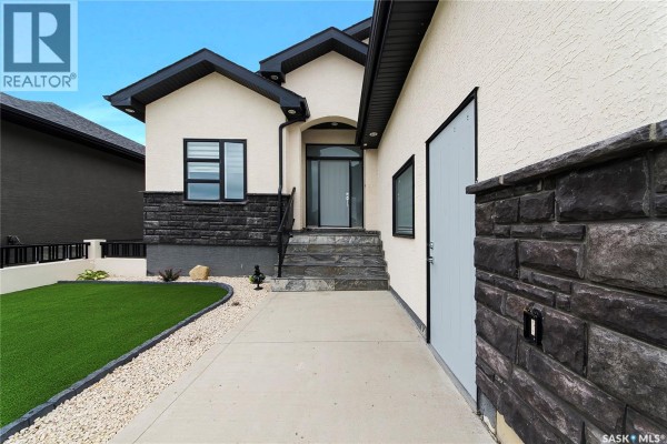 Pathway leading to the front entrance of a house with stone steps and siding. - 733 Gowan Road, Warman