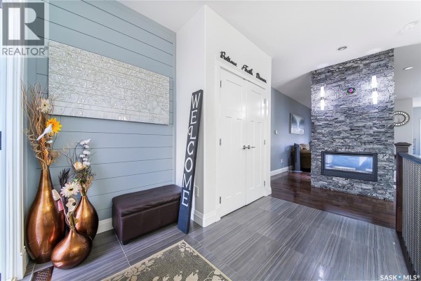 Interior foyer with blue shiplap walls, a modern fireplace, and decorative vases. - 733 Gowan Road, Warman