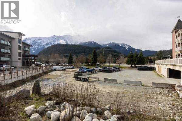 A bare lot with a few parked cars and a truck, with snow-capped mountains in the background. - 7340 Crabapple Court, Pemberton