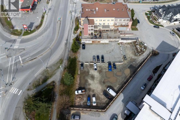 Overhead view of an empty lot with parked cars, bordered by a creek and buildings. - 7340 Crabapple Court, Pemberton