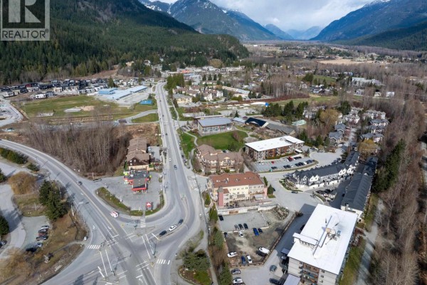 Aerial view of a Pemberton street with commercial buildings, residential areas, and mountains. - 7340 Crabapple Court, Pemberton