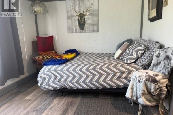 Bedroom area with a bed, pillows, a chair, and a decorative deer head on the wall. - 7344 Route 117, Miramichi Bay
