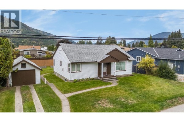 Empty living room with light wood floors, white walls, and large windows with curtains. - 735 10th Avenue, Montrose