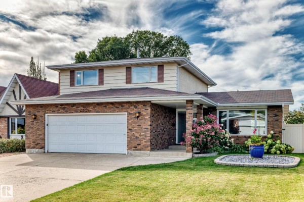 Exterior view of a two-story house with a brick lower half and beige siding upper half. - 7355 18 Av Nw, Edmonton