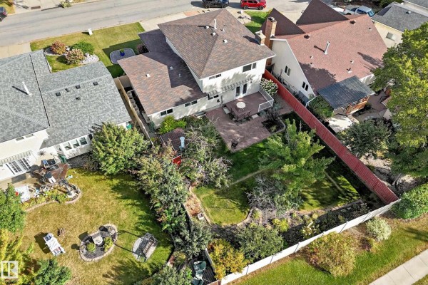 Aerial view of the backyard of a two-story house with a patio and mature trees. - 7355 18 Av Nw, Edmonton