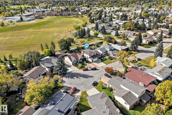 Aerial view of the neighborhood showing houses, streets, and a nearby park. - 7355 18 Av Nw, Edmonton