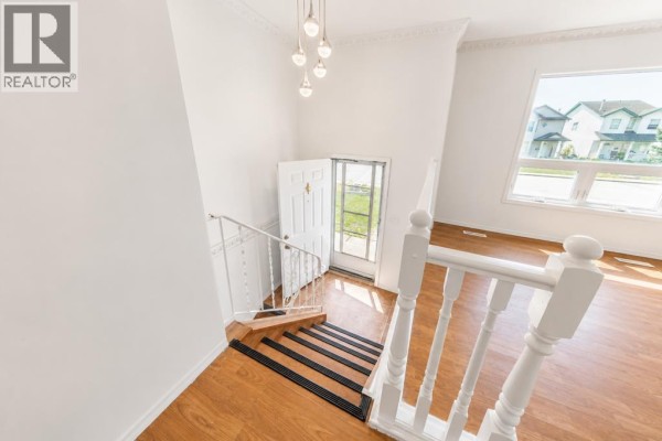View from the top of the stairs looking down at the front door and adjacent living area with wood floors. - 7363 59 Avenue, Red Deer