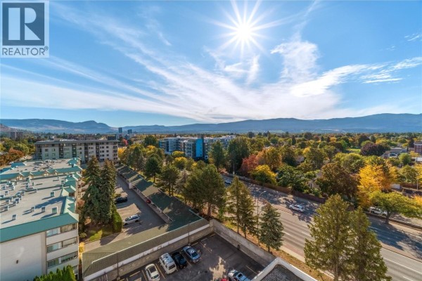 View from balcony of a suburban neighborhood with trees and a distant mountain range. - 737 Leon Avenue Unit# 1007, Kelowna