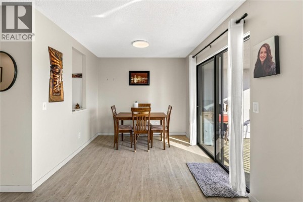 Dining area with a wooden table and chairs, sliding glass doors to balcony. - 737 Leon Avenue Unit# 1007, Kelowna