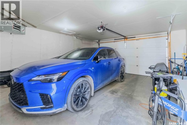 Interior of a two-car garage with a blue SUV parked inside and a white garage door. - 738 4th E, Saskatoon