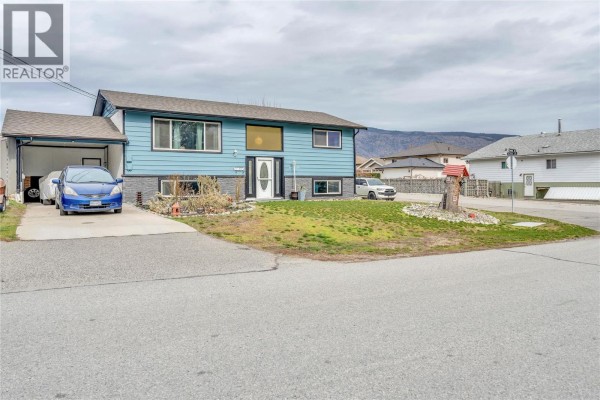 Side view of the blue house with a driveway and garden area. - 738 Kettle Avenue, Oliver