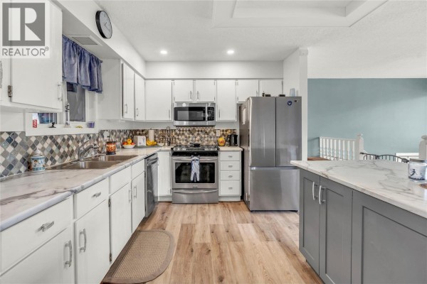 Modern kitchen with stainless steel appliances, white cabinets, and tiled backsplash. - 738 Kettle Avenue, Oliver