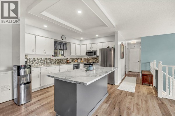Spacious kitchen island with marble countertop, open layout, and bright lighting. - 738 Kettle Avenue, Oliver