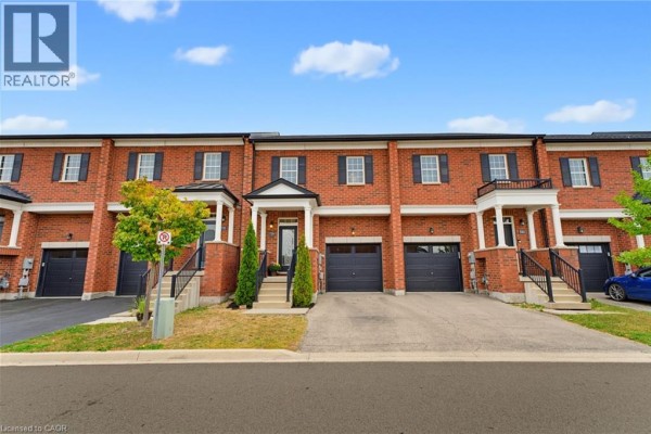 Street view of brick townhouses with garages and front entrances, one car visible. - 739 Banks Crescent, Milton