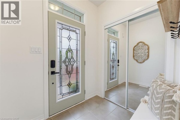 Entranceway with light green door, stained glass, tiled floor, and mirrored closet. - 739 Banks Crescent, Milton