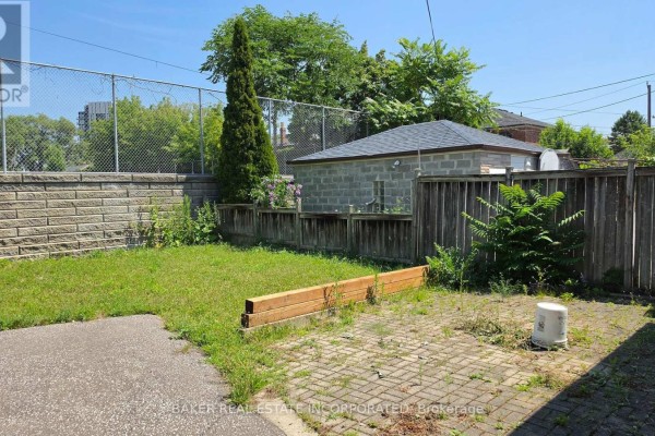 Fenced backyard with a concrete patio, grass area, and a detached garage. - 739 Vaughan Road, Toronto
