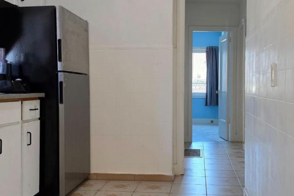 Kitchen view with a stainless steel refrigerator, white tiled walls, and doorway to hallway. - 739 Vaughan Road, Toronto