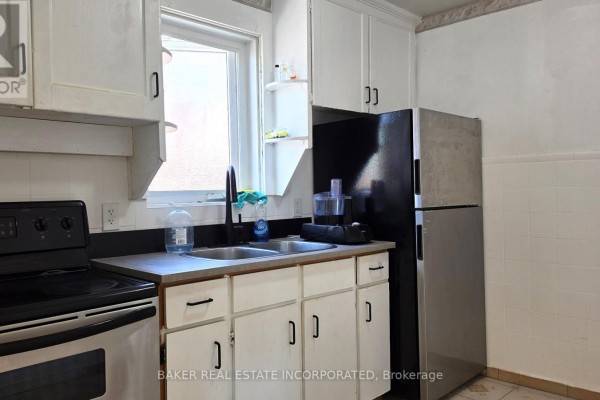 Kitchen sink area with white cabinets, black countertops, stainless steel appliances, and a window. - 739 Vaughan Road, Toronto
