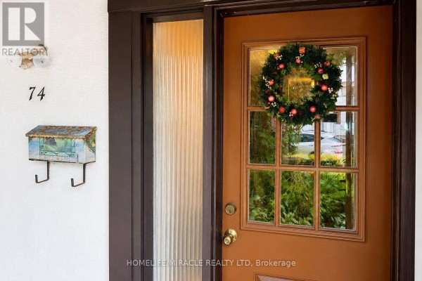 Close-up of the front door with a glass inset and a holiday wreath, next to house number 74. - 74 - 2651 Aquitaine Avenue, Mississauga
